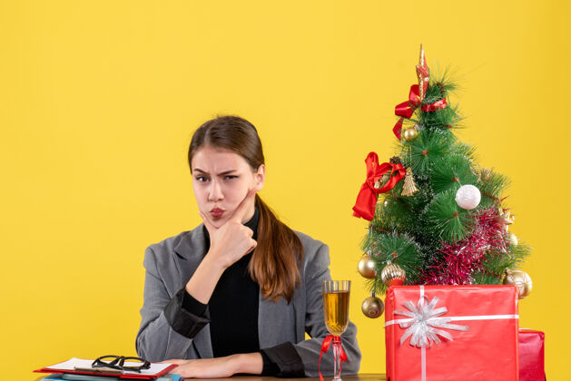 思考前视图思考女孩坐在办公桌前圣诞树和礼物微笑坐人
