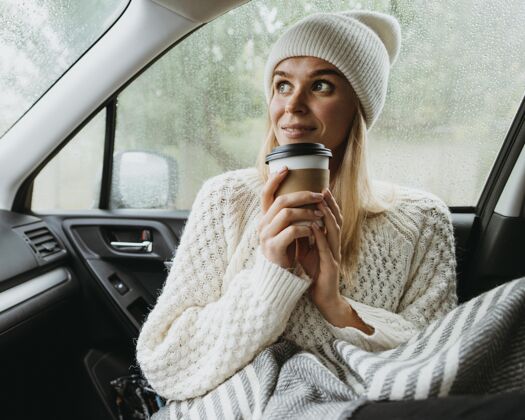 户外金发女人在车里拿着一杯咖啡假日年轻季节