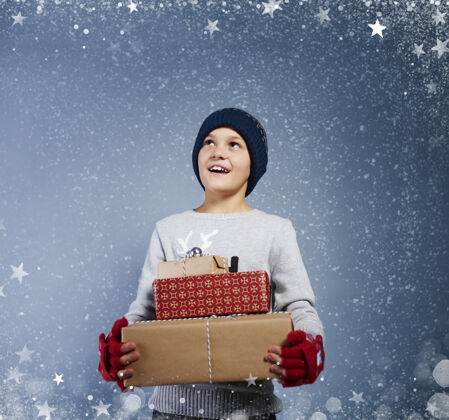 编织带着圣诞礼物的男孩在雪中飘落接受天真圣诞礼物
