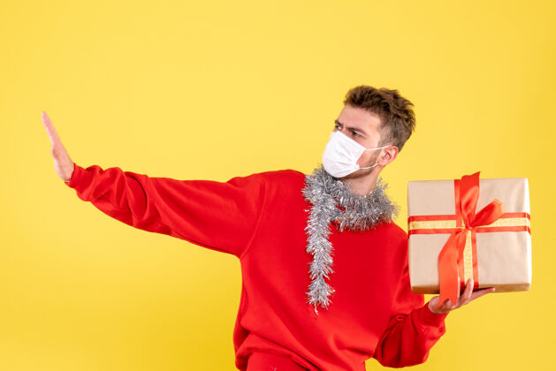 不育正面图：戴着无菌面具的年轻男性正在过圣诞节礼物颜色Covid