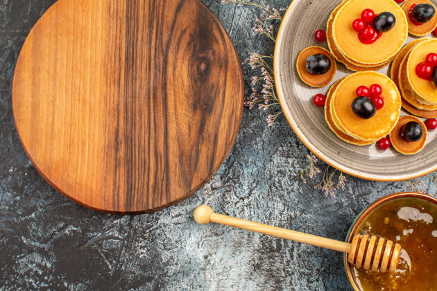 食物近距离观看圆形木制砧板水果煎饼和蜂蜜木勺棍子金属