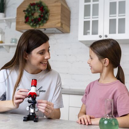 孩子笑脸女孩和妈妈用显微镜做实验化学家试管实验