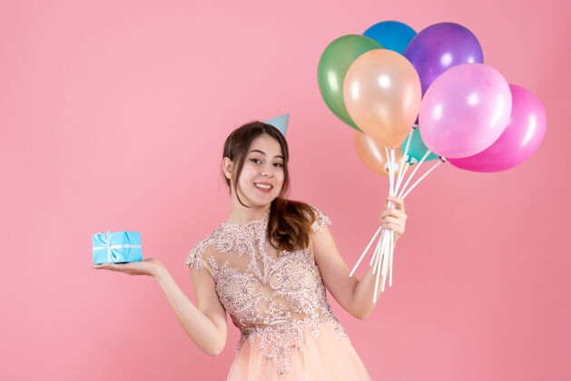 公主快乐的派对女孩 戴着派对帽 手里拿着五颜六色的气球和粉红色的礼物快乐礼物举行