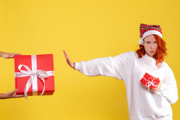 女人黄色墙上年轻女子拿着小礼物拒绝大礼物的正面图大情感圣诞节