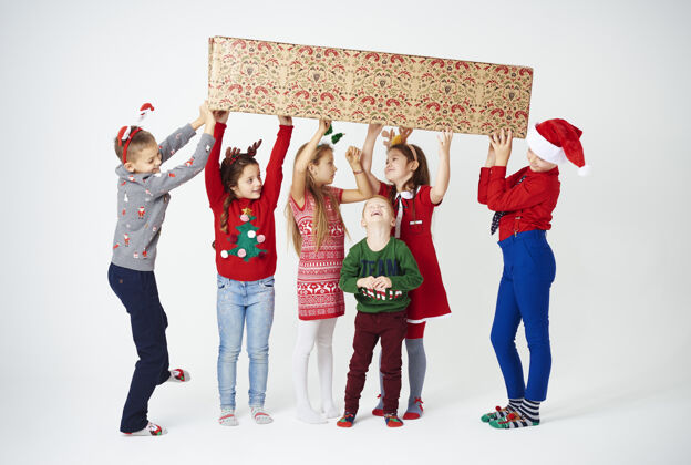 庆祝一群准备拿着大礼物盒的孩子们圣诞节站立结合