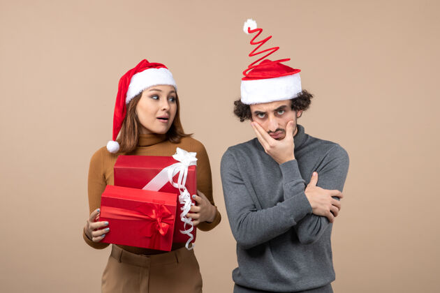 圣诞老人新年气氛喜庆的概念与搞笑酷可爱的情侣戴着红色圣诞老人帽重点放在灰色的东西帽子帽子心情