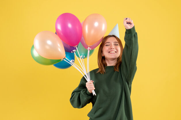 吹正面图是一位年轻的女士 手里拿着五颜六色的气球生日乐趣颜色