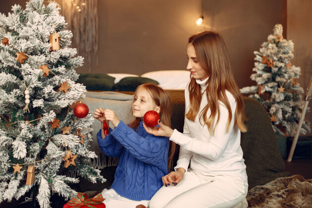 玩具人们在为圣诞节做准备母亲在和女儿玩耍一家人在节日的房间里休息孩子穿着蓝色毛衣杉木绿色装饰