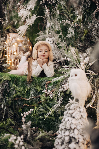 自然漂亮的白种人小孩 长着金色的长发 躺在圣诞气氛中 周围有很多装饰树和猫头鹰装饰新庆祝