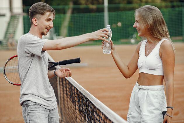 生活方式一对年轻夫妇在网球场上两个网球运动员休息一下人球拍运动