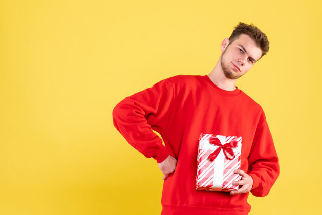 服装正面图：穿着红色衬衫的年轻男性 带着圣诞礼物圣诞节年轻男性情感