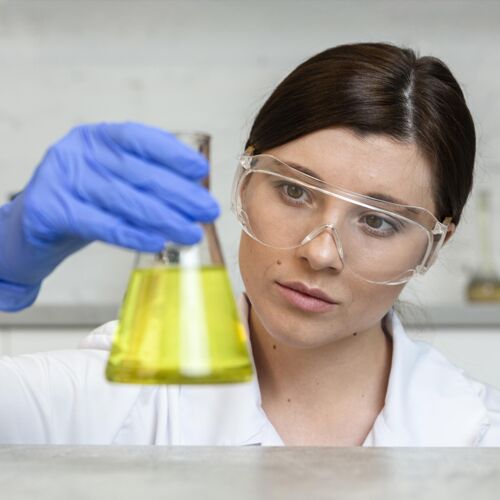 化学戴着安全眼镜拿着试管的女研究员测试女人研究员