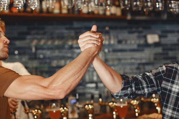 晚上和最好的朋友见面两个穿着休闲服的快乐的年轻人一起坐在酒吧里聊天喝啤酒足球酒吧朋友
