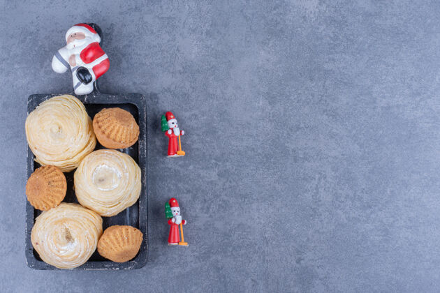 吃美味的糕点和圣诞玩具在灰色的表面玩具球面包房