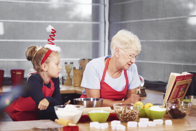 烹饪奶奶和孙女在准备圣诞蛋糕烘焙一只援助之手布丁