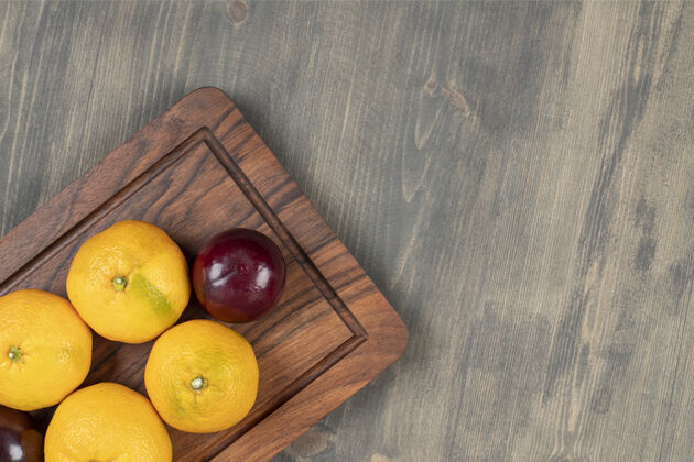 甜味木砧板上的甜橘子和李子高质量的照片柑橘木制营养