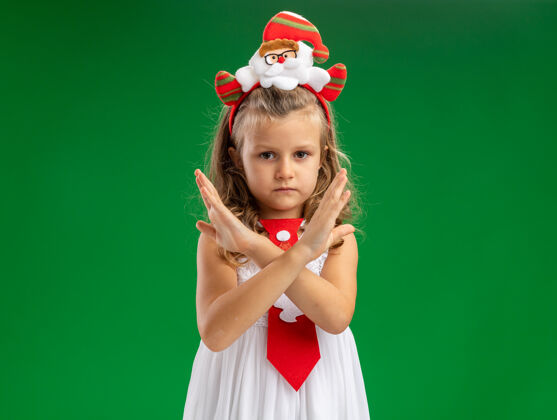 小严格的小女孩戴着圣诞发箍 打着领带 在绿色背景上显示出不孤立的姿态圣诞节领带显示