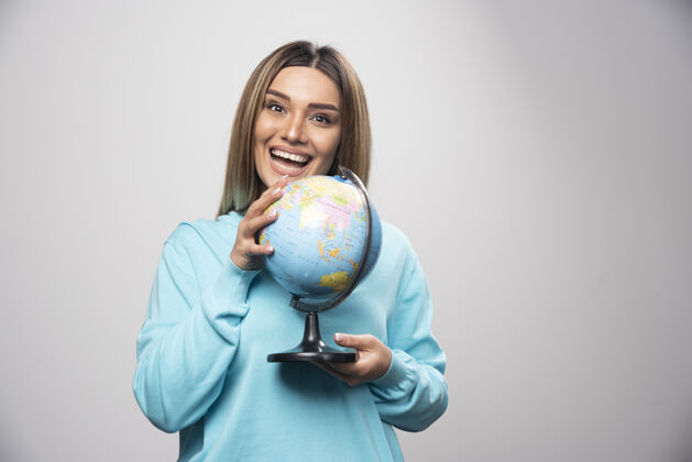 地球穿着蓝色运动衫的金发女孩拿着一个地球仪 猜着地点 玩得很开心金发地理地球