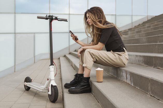 Escooter年轻女子正在浏览她的手机年轻人生活方式女士
