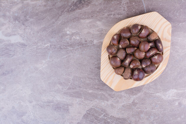 食物棕色栗子放在大理石上的木盘里扁豆维生素干燥