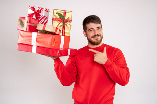 年轻身穿红衫的年轻人拿着圣诞礼物站在白墙上的正视图礼物圣诞节前面