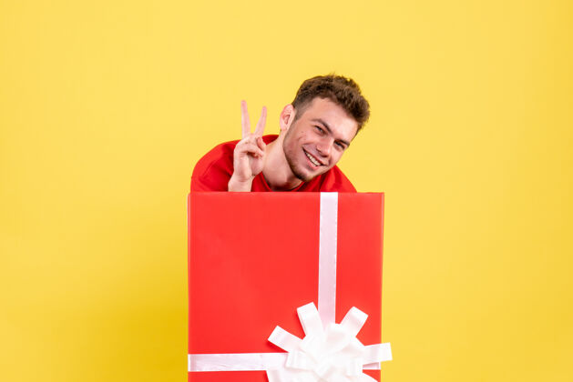 颜色正面图身着红衫的年轻男子站在礼物盒内微笑着圣诞节节日年轻男性