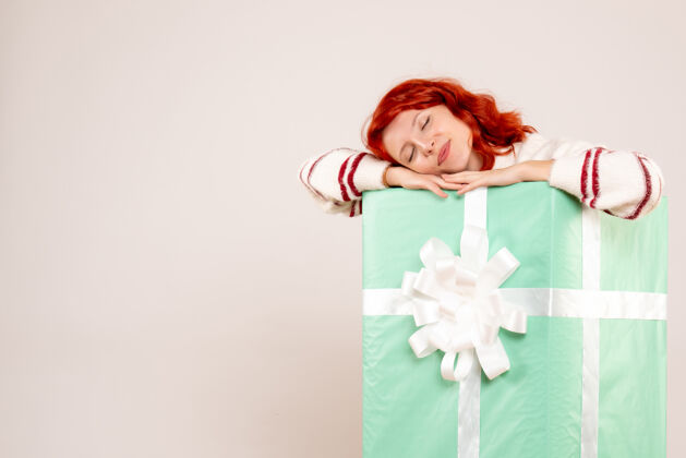 快乐年轻女子躲在圣诞礼物里睡在白墙上的前视图盒子节日微笑