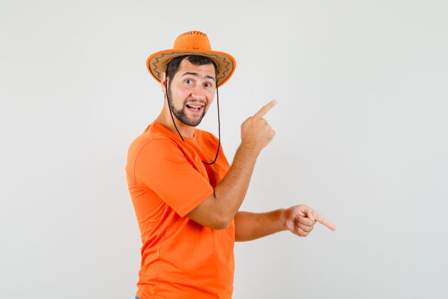 表情身穿橙色t恤 戴着帽子的年轻人手指上下 神情愉悦 俯瞰前方模特男人帽子