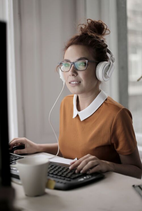 眼镜一个戴着眼镜和耳机在灯光下工作的女性的垂直镜头职业互联网灯光
