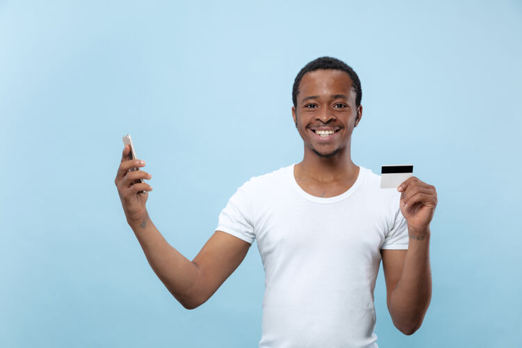 选择一个身穿白衬衫 手持卡片和智能手机的年轻非裔美国人的肖像帅气非洲人