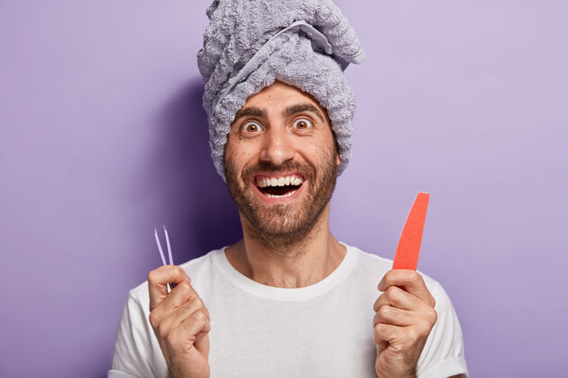 治疗快乐的男人拿着指甲锉和镊子 去美容院或家里做美容 做指甲矫正 头上有毛巾spa镊子Spa惊讶