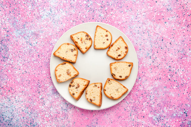 顶部顶视图蛋糕片与葡萄干内板上的粉红色背景蛋糕烤甜饼干颜色派糖饼干盘子颜色葡萄干