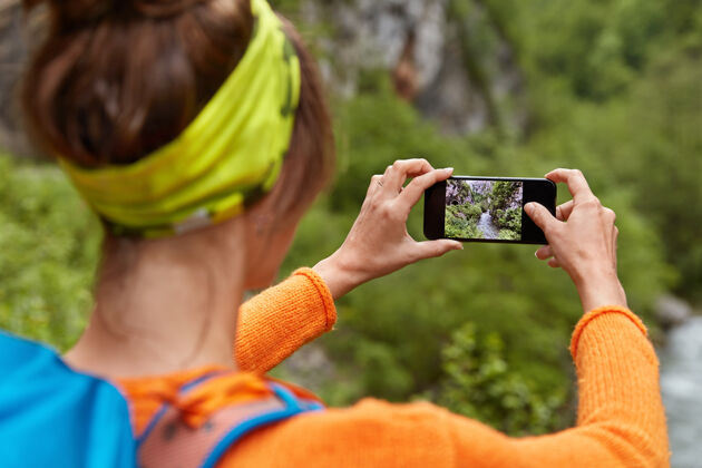 智能手机在智能手机上 一个女游客的倒向镜头在峡谷中拍摄了一张河流的照片 可以在社交网络上发布技术水平设备