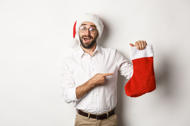兴奋圣诞快乐 节日概念快乐的成年人收到礼物在圣诞节袜子 看起来很兴奋 戴着圣诞帽节日冬天胡须