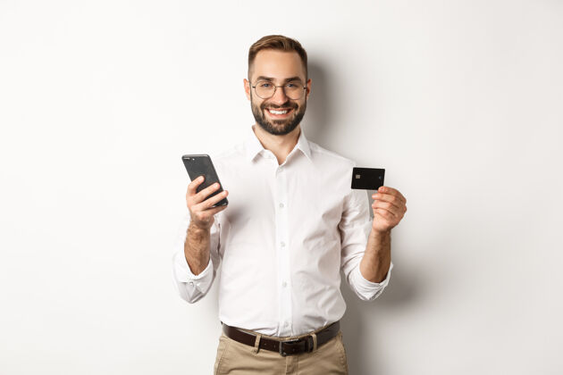 支付商务和在线支付微笑的男性企业家用信用卡和手机购物 站着雇主老板在线