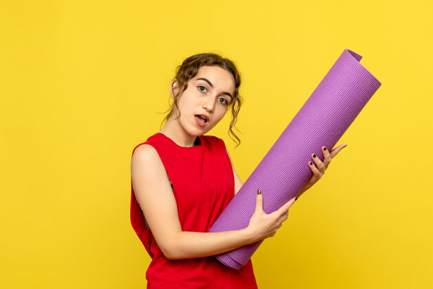 地毯黄墙上紫色地毯的年轻女子的正视图成人女性生活方式