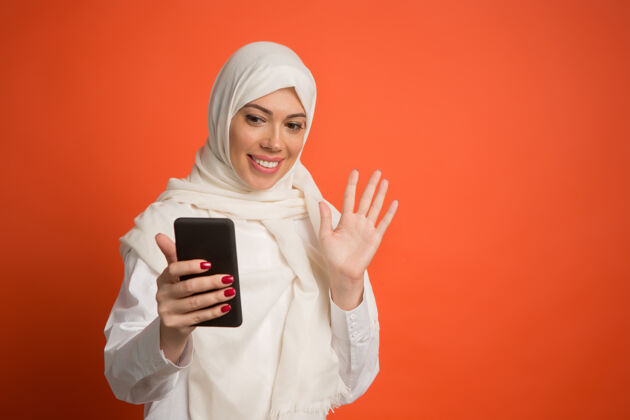 表情戴着头巾的快乐阿拉伯女人用手机自拍肖像成人传统