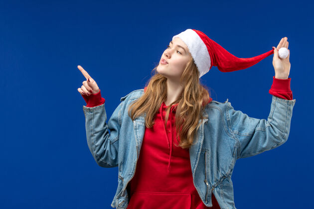 年轻女性正面图蓝色空间上戴着红色圣诞帽的年轻女性时尚成人欢快