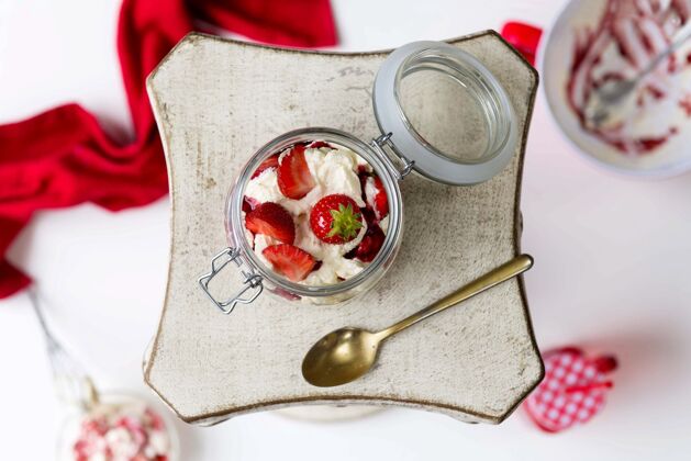 甜食水平拍摄一罐草莓和白色奶油 用勺子放在一个方形盘子里美味浆果冷冻