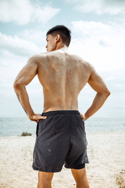 健康年轻健康的男子运动员在海滩上做深蹲健身高加索健美