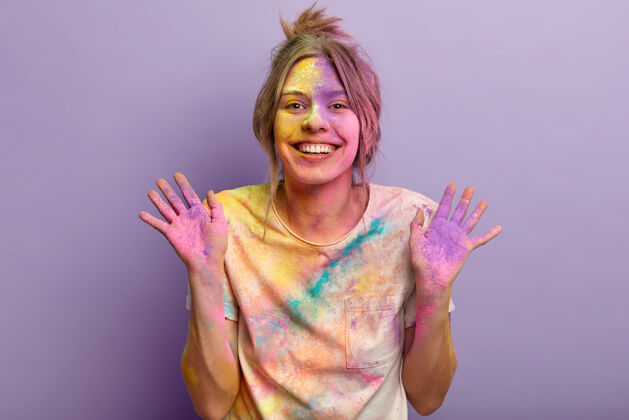 高兴快乐可爱的年轻女子展示着五颜六色的手掌 先参观完胡里节后心情大好 玩弄色彩 在紫色的墙上涂上彩粉节日五颜六色高兴