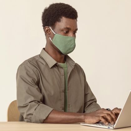 技术戴着口罩用笔记本电脑的男人医疗面具工作室摄影