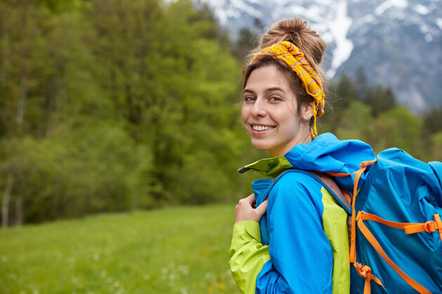 徒步旅行者心满意足的旅行者 带着温和的微笑 戴着黄色的头带和休闲服 背着大背包背包Anorak心情