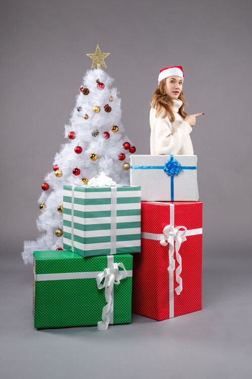 礼物年轻的女性在灰色的圣诞礼物周围包圣诞树圣诞