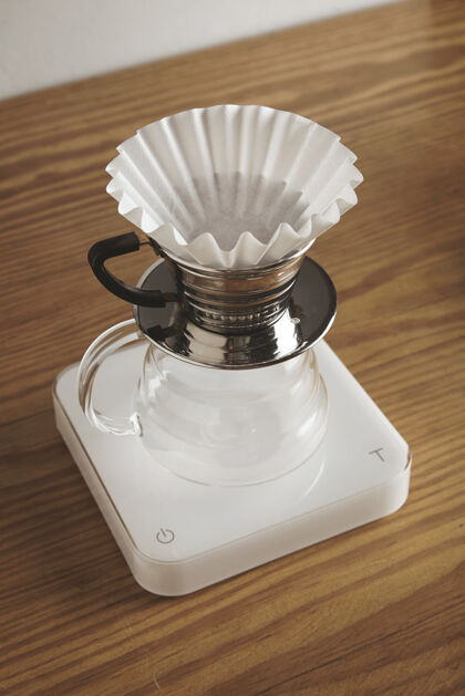 专业的漂亮的空滴咖啡机 顶部有闪亮的铬杯和干净的纸过滤器 可以准备过滤后的咖啡咖啡厅的木桌上的白色砝码隔离倒酒热的浓缩咖啡