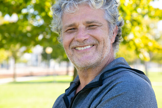 退休快乐的灰色头发的男人穿着运动服站在外面 微笑着特写镜头成熟的运动人士或积极的生活方式的概念姿势老年人积极