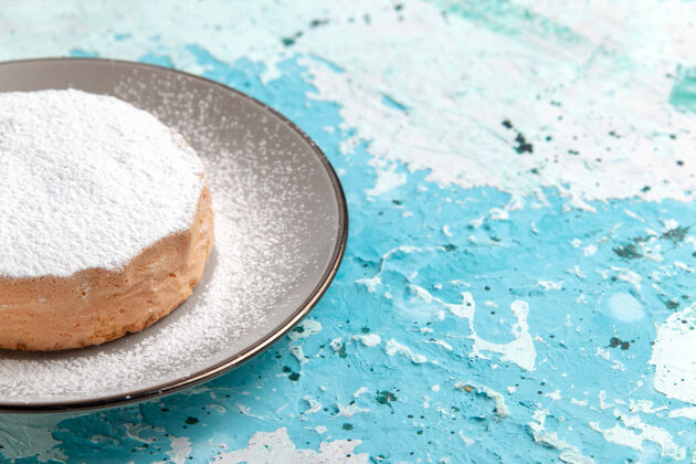 粉末正面近距离观察圆形蛋糕 里面有糖粉 盘子上有浅蓝色的表面蛋糕烤饼干糖甜茶的颜色烘焙盘子查看