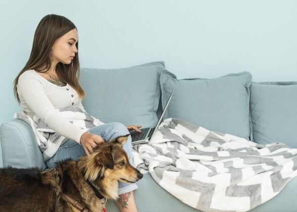 Covid19流感大流行期间 一名妇女在家里用笔记本电脑抚摸她的狗狗隔离防护