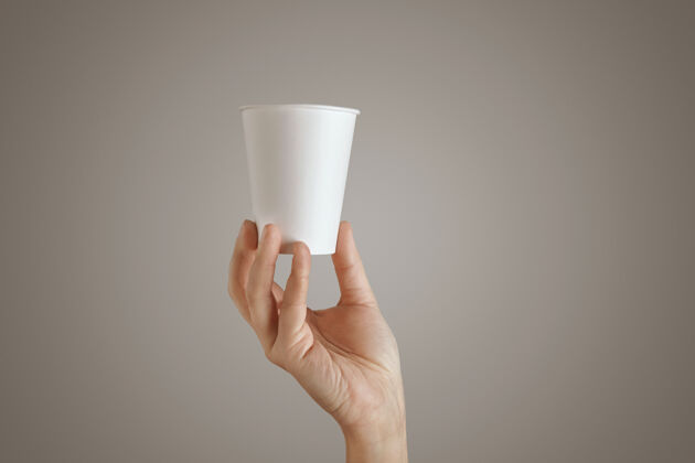 容器女人的手从底部拿着空白的空带走纸杯 呈现在中间 侧视 孤立 无法辨认餐咖啡茶