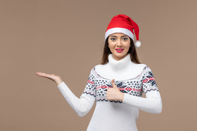 女人正面图棕色背景上微笑的年轻女子圣诞节快乐帽子可爱